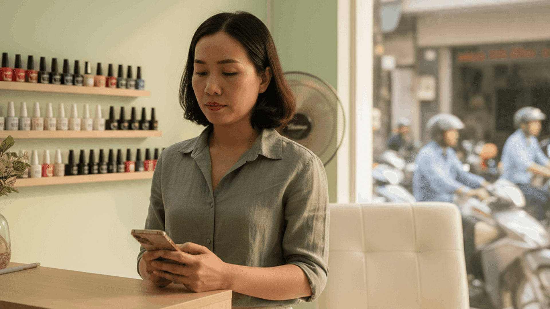 Thợ nail đứng ở quầy, ngập ngừng khi nói chuyện với một khách quen đang chờ